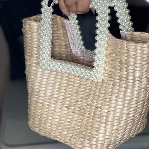 The beautiful fashionable purse has pearls for handle an a pink silk inside